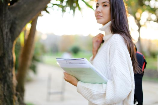 Focus on documents in chinese woman hands outdoors. Concept of asian student.