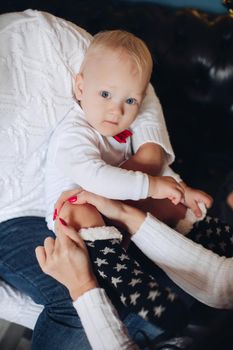 Cute little baby being caressed by his loving parents while having fluffy Christmas socks on. Holiday concept