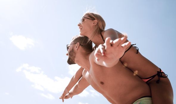 Handsome man giving piggy back to his girlfriend.