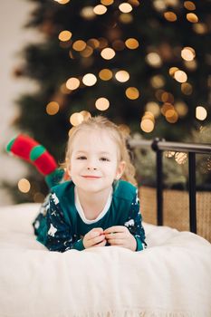 Happy child in christmas socks rejoices on the bed