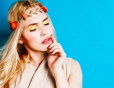 young blond woman dressed like ancient greek godess, beautiful girl hands manicured red nails on blue background copyspace close up