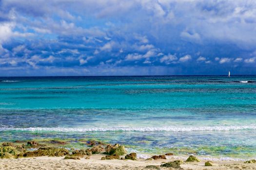 The view from the shore of a beautiful tropical sea with a beach. The warm waters of the ocean bathe colorful stones in the water. Vacation concept.