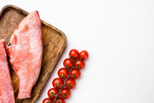 Raw red sea bass fish set, on wooden serving board, on white stone table background, top view flat lay, with copy space for text