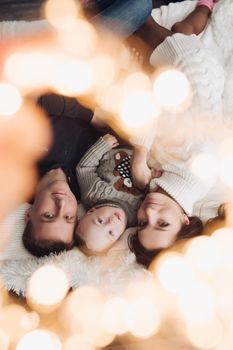Upside down photo of a lovely little family laying down together under the Christmas lights