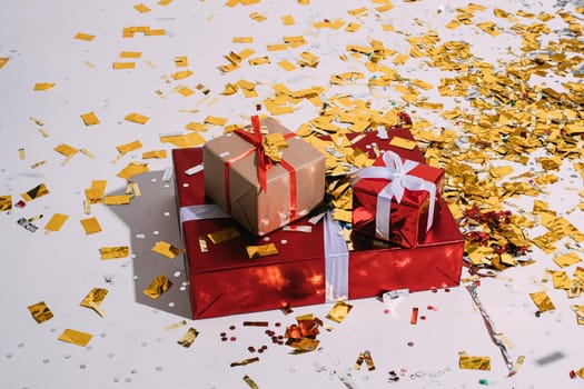 Stock photo of three different sized Christmas gifts wrapped in wrapping paper and bow and scattered golden confetti.