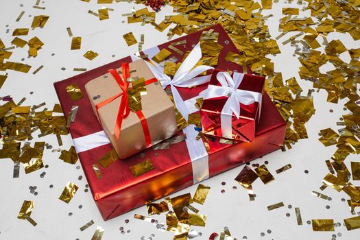 Stock photo of three different sized Christmas gifts on the floor covered with golden confetti.