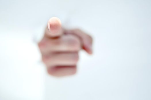 man's hand breaking through the paper wall and pointing at you .photo with copy space