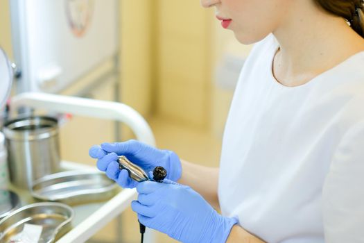 Caucasian cosmetlogist standing with microblading device at beauty salon. Concept of permanent makeup artist and cosmetology equipment.