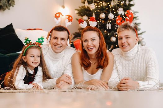 Close-up portrait of a happy family lying near a Christmas tree celebrating a holiday.