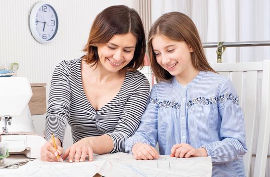 Novice tailor learning from her master art of making templates for sewing