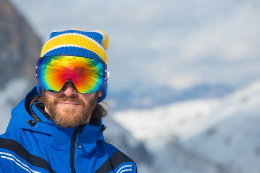 Close up portrait of man skier in hat and ski goggles mask looking at mountain range Col Gallina Cortina d'Ampezzo Dolomites