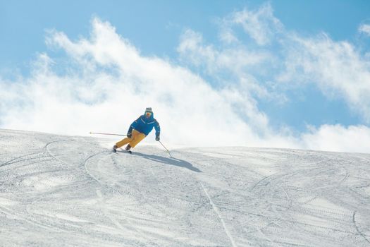 Male skier in blue and yellow clothes on slope with mountains in the background at Cortina d'Ampezzo Col Gallina Sella Ronda skiing resort area Dolomiti Italy