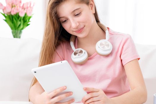 cute teen, browsing interesting articles on internet on her personal tablet computer
