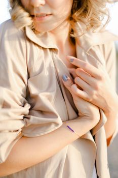Close up woman with manicure and without makeup wearing coat. Concept of spring fashion and beauty.