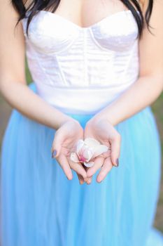 Brunette woman keeping magnolia flower in hands. Concept of beauty and nature.