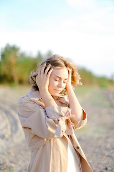 Closeup caucasian girl standing on beach and holding head. Concept of enjoying summer and resting outside.