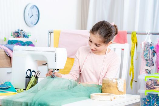 smiling little girl seamstress working at the sewing machine