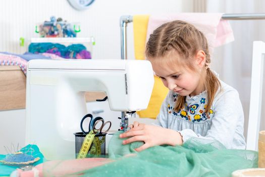 Little girl using sewing machine to make crafts in the workshop