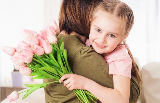 Cute kid embracing mother with festive bouquet, Mothers day