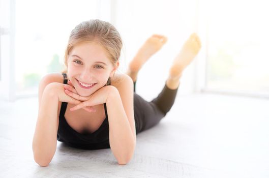 Cute smiling teenager girl lying on a floor in light room