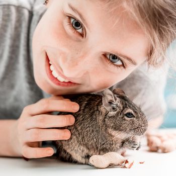 Portrait of young girl with degu squirrel and nuts, close-up.