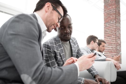 two employees look and read on the smartphone screen.