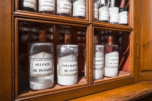 BEAUNE, FRANCE - AUGUST 03,2019: Shelf with medicines in glass bottles in a retro pharmacy