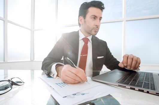 businessman uses a laptop sitting at his Desk.close up