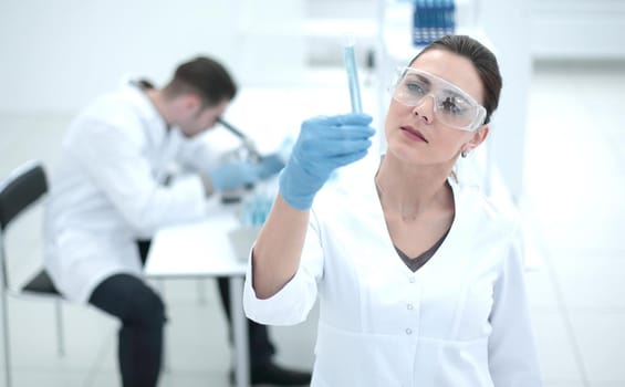 serious female scientist looks at the tube with the results of the analysis.photo with copy space