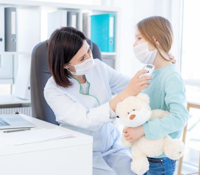 Cute little girl in face mask at doctor office