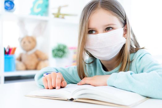 Beautiful little girl in medical mask reading book
