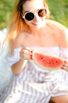 Young caucasian girl in sunglasses eating watermelon. Concept of healty food and summer season, vegeterian lifestyle.