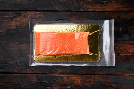 Fillet of red vacuum packed fish set, on old dark wooden table background, top view flat lay, with copy space for text
