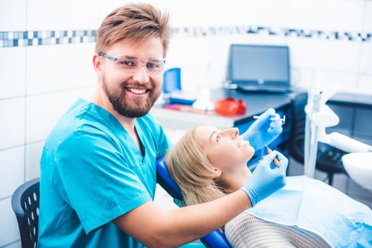 Smiling dentist treating patient in clinic
