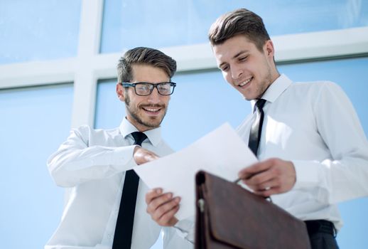 Businessman holding and getting out documents with graphs from his leather briefcase.