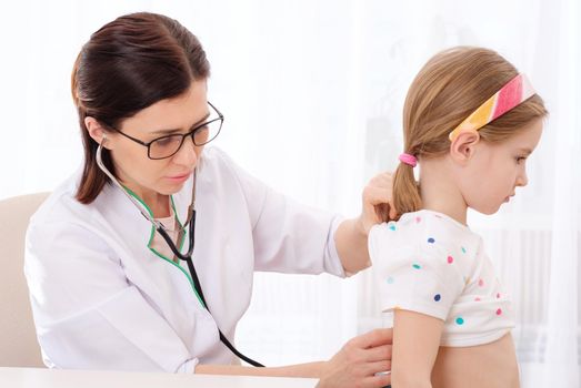 Female doctor listening to little girls internal sounds with stethoscope