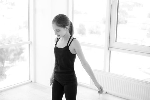 Pretty young girl dancer on a floor in light room, black and white