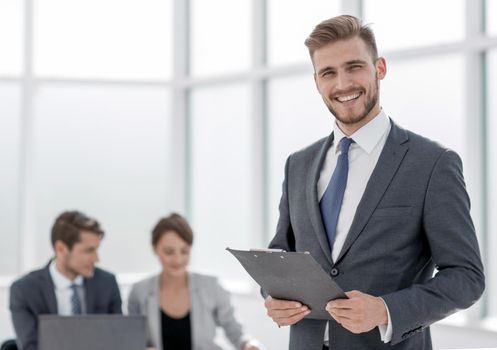 smiling businessman with a clipboard on the background of the office.photo with copy space