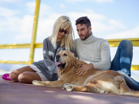 Couple With A Dog enjoying time  together On The Beach at autumn day