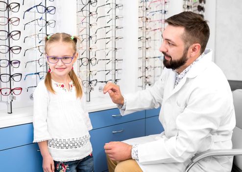 Little girl and doctor ophthalmologist choose glasses