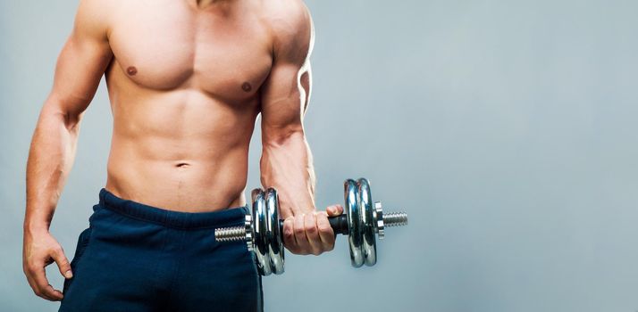 attractive athletic male torso with dumbbells with copy space