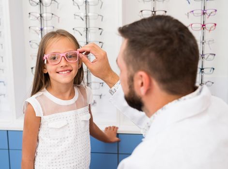 Little girl and doctor ophthalmologist choose glasses