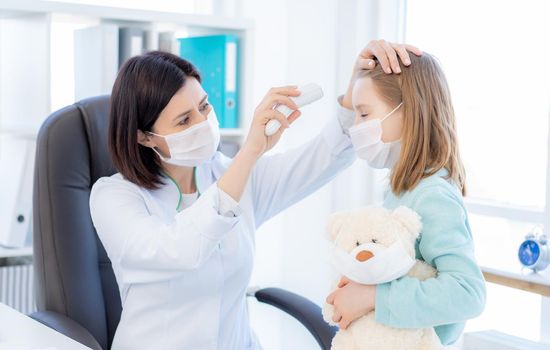 Doctor measuring temperature of little girl in light office