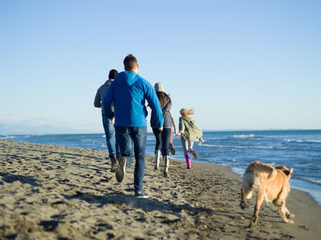 group of young friends spending day together running on the beach during autumn day