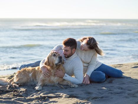 Couple With A Dog enjoying time  together On The Beach at autumn day