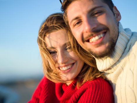 portrait of young couple having fun on beach during autumn sunny day