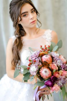 Portrait of beautiful caucasian brunette caucasian bride with flowers at studio. Concept of bridal photo session and beauty.