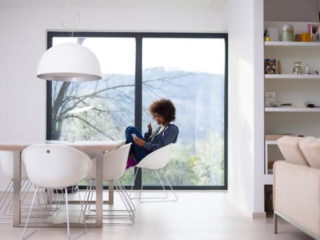 Handsome young african american woman drinking coffee and using a mobile phone at  home