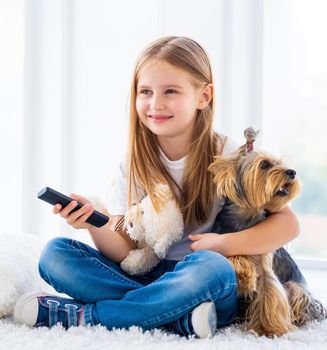 Cute girl and her dog switching channels with tv remote