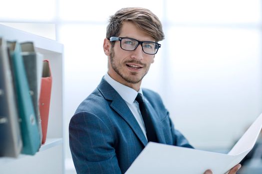 Young businessman working with documents looking through papers in folder